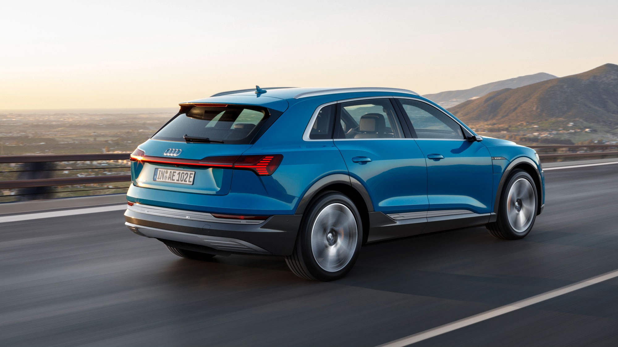 Blue Audi e-tron driving on highway sunset