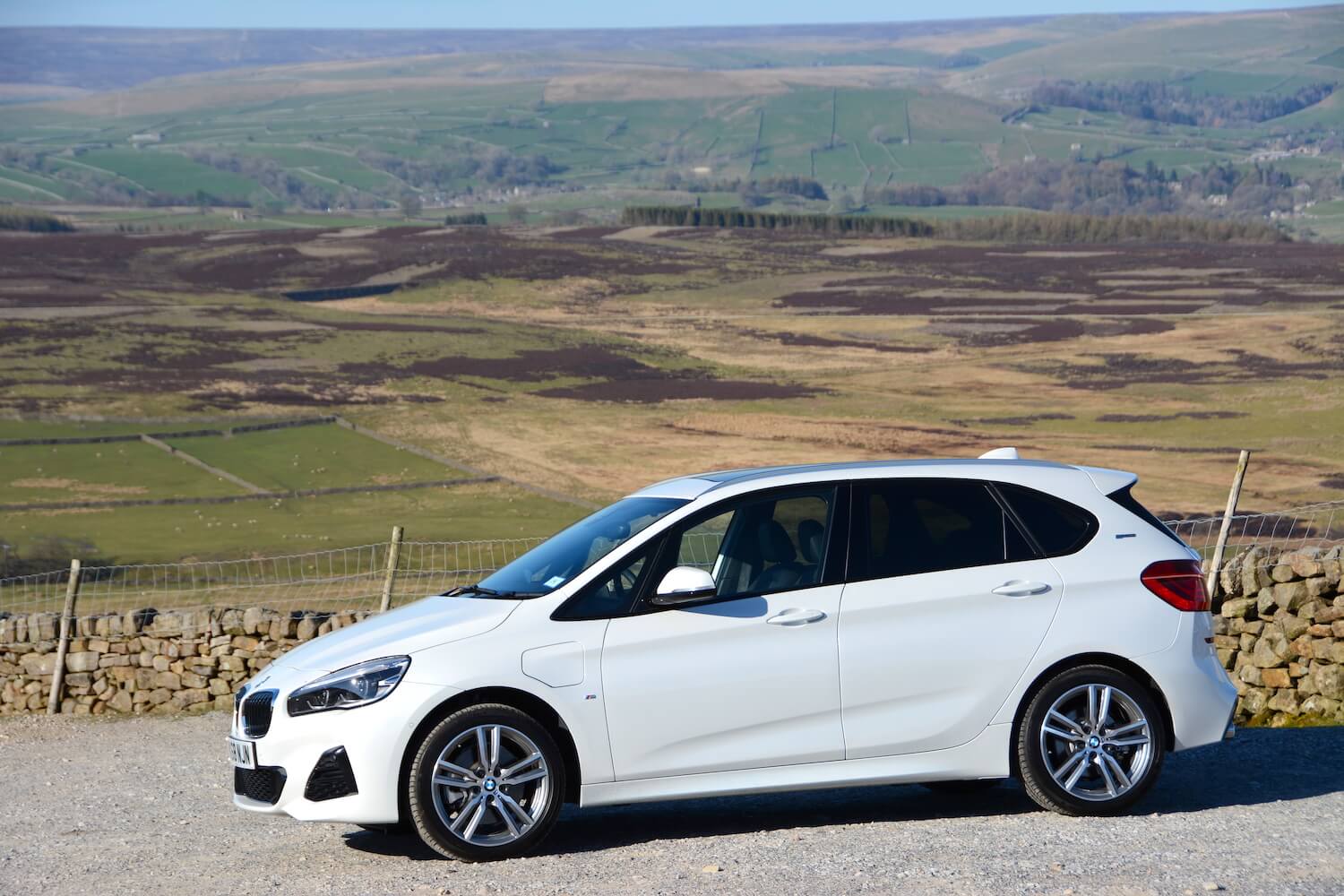 White BMW 225xe plug-in hybrid parked near country fields