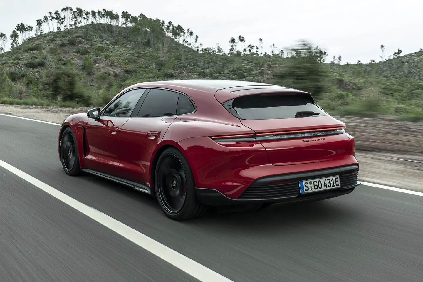 Red Porsche Taycan Turbo S driving with rocky backdrop