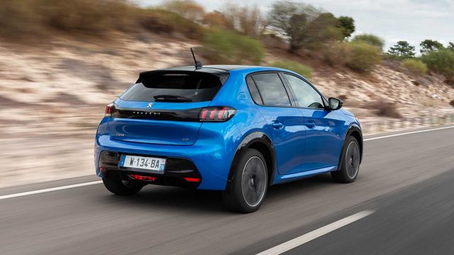 Blue Peugeot e-208 driving on road with rocky backdrop