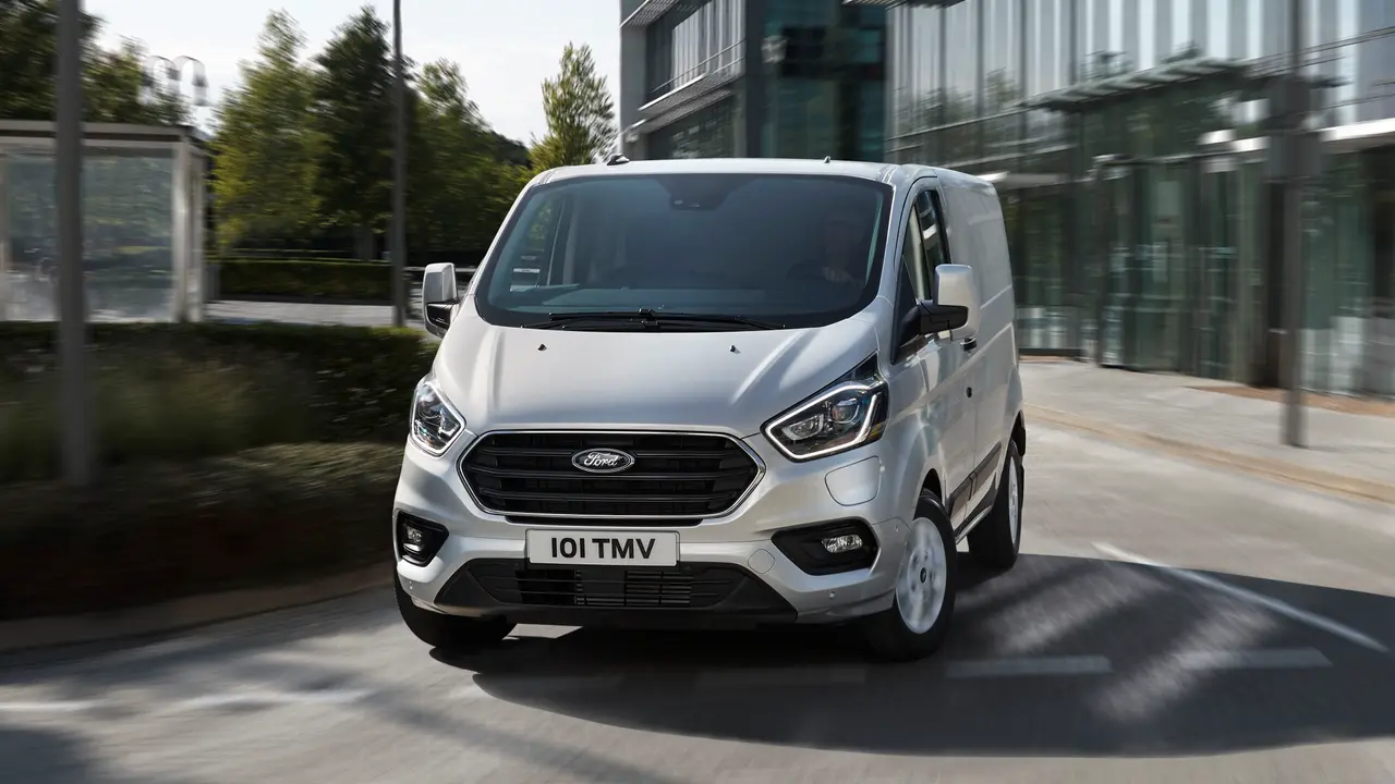 Silver Ford Transit Custom Plug-In electric turning corner in city area