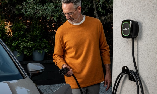 man plugging EV on charge with wallbox charger on wall